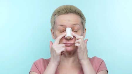 a woman with a bandage after rhinoplasty scratches her nose under a castの写真素材