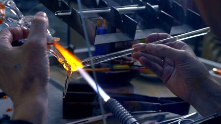 Closeup of male hands. make glass crafts by melting glass on a burner