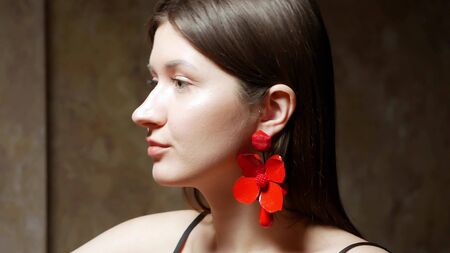 young beautiful stylish girl wears earrings. the dark backgroundの写真素材