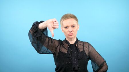 woman showing thumbs down. blue background. gestures and emotions