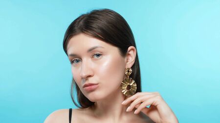 young beautiful stylish girl wears earrings. blue backgroundの写真素材