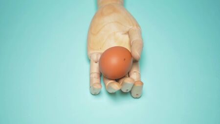 creative design. minimalism. wooden hand holding an egg. blue background