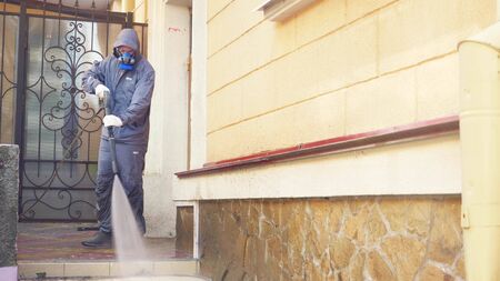 the man in the mask handles the house outside with high pressure washerの写真素材