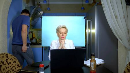 A woman in shorts and blouse working remotely from home in the kitchenの写真素材