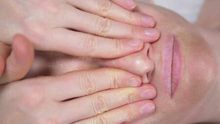 masseur gives woman anti-aging facial massage in spa. closeupの写真素材