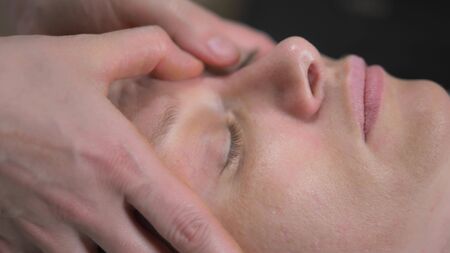 masseur gives woman anti-aging facial massage in spaの写真素材