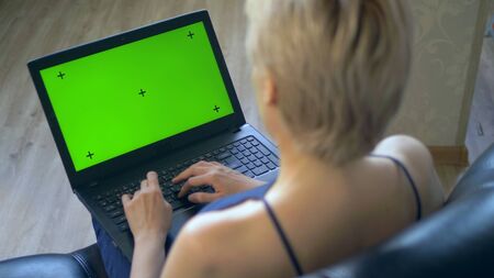 chroma key on laptop screen. look over your shoulder. woman uses laptop at homeの写真素材