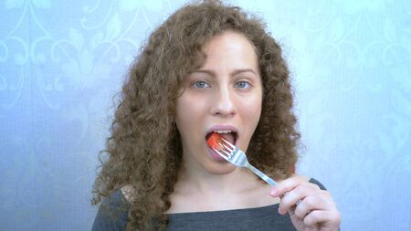 beautiful curly girl eating a salad with tomatoes. portraitの写真素材