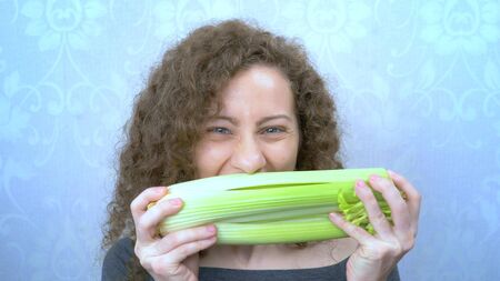 portrait of a beautiful girl happily eating celery stalksの写真素材