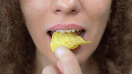 closeup of the lips. beautiful curly girl with pleasure eats potato chips
