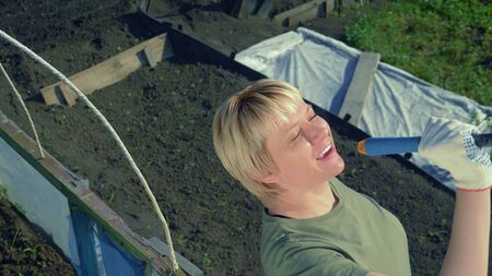 beautiful young woman sings holding a rake like a microphoneの写真素材