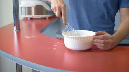 closeup. A man beats eggs with flour. make dessert in the home kitchenの写真素材