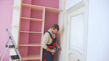Young male furniture assembler assembles a built-in wardrobeの写真素材