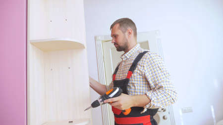 Young male furniture assembler assembles a built-in wardrobeの写真素材