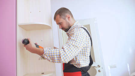 Young male furniture assembler assembles a built-in wardrobeの写真素材
