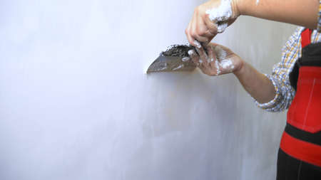 close-up of a hand. a man applies plaster with a trowel to the wallの写真素材