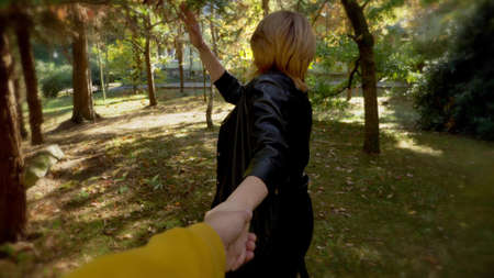 Follow me. a woman leads a man by the hand in the park. first-person viewの写真素材