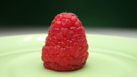 extremely close-up, detailed. lonely berry of ripe red raspberries on a plate
