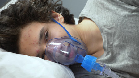 oxygen mask on the face of a guy lying on a bed in a hospitalの写真素材