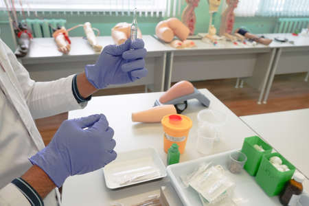 Doctors or nurses hands in the sterile blue medical gloves holding ampoule with drug.