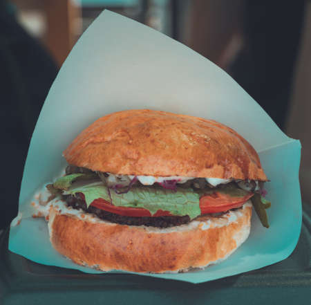Juicy,appetizing and tempting burger in craft paper cooked at barbecue outdoors. Street food, fast food.の写真素材