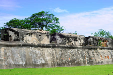 Old white wall with blue sky and green grassの写真素材