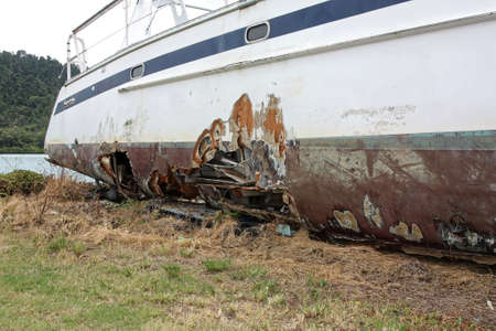 damaged yacht with hole in the side on landの写真素材