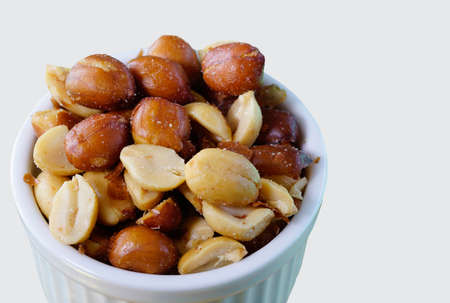 close up of salted peanuts in a white bowl with white background