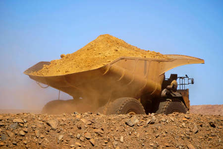 Gold mine operation in open gold mine pit with large haul truck leaving with dirt