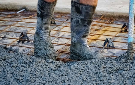 one man at work pouring concrete view of legs with gumboots in wet concreteの写真素材