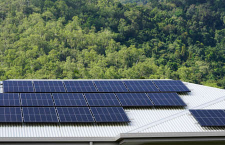 solar panels on the roof of a house with rainforest in the background