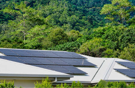 solar panels on the roof of the house with rainforest in the background