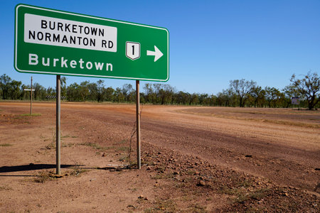green road sign to Burketown QLD Australia dirt road and bushes in the background