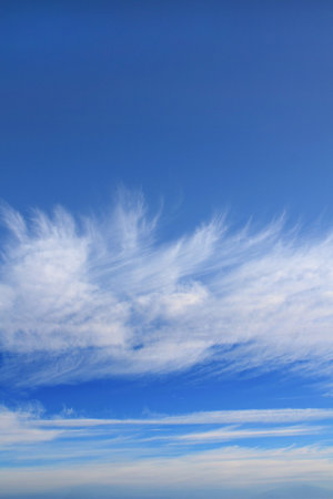 Wispy clouds create a stunning pattern against a bright blue sky on a sunny day.の写真素材