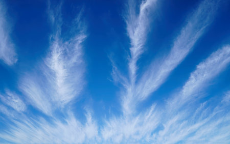 Wispy clouds create a stunning pattern against a bright blue sky on a sunny day. The scene depicts the vastness and beauty of the skyの写真素材