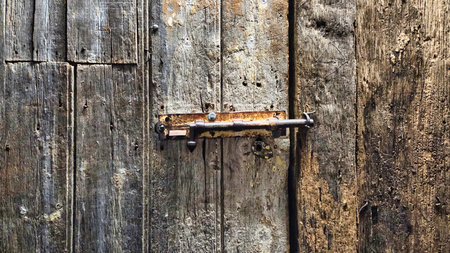 Type of door lock or door latch. A sliding bolt lock or a barrel bolt or surface lock on a weathered wooden doorの写真素材