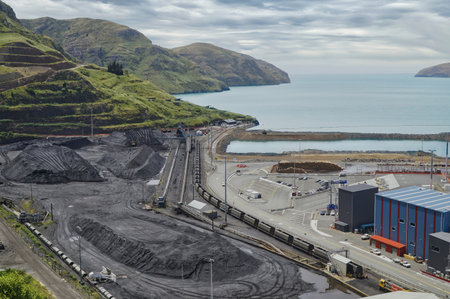 Industrial coastal scene featuring coal stockyard, rail lines, and port infrastructure set against a...