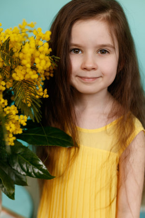 Girl with yellow mimosa bouquet on turquoise background
