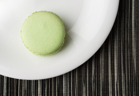 Green Macaron on White Plate on striped backgroundの写真素材