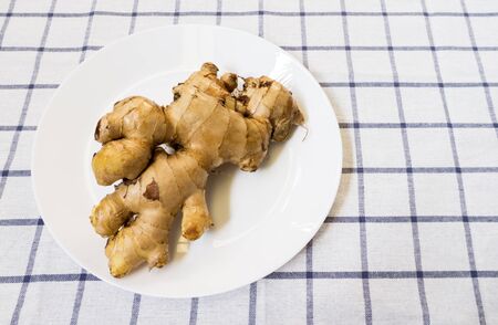 Brown Galangal Root on White Plate Placed on Big Squared Backgroundの写真素材
