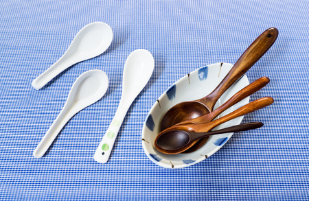 Set of Wooden Spoon in White Bowl with Three Ceramic Spoon on Blue Backgroundの写真素材