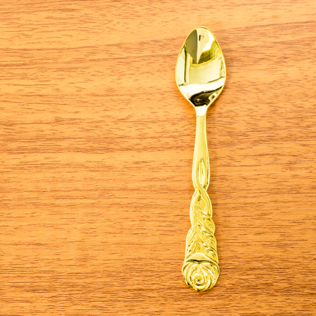 Vintage Shinny Golden Spoon with Thai Pattern Place on Wooden Backgroundの写真素材