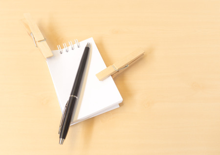 Two Clothespins with Black Pen and White Notepad on Wooden Tableの写真素材