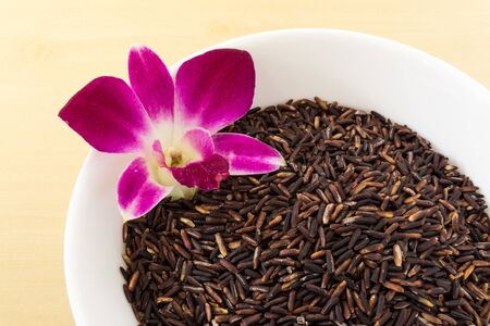 Thai Brown Rice Berry in White Bowl with Orchidの写真素材