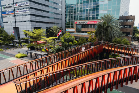 Jakarta, Indonesia - October 2022: an asian woman crossing a pedestrian bridge in the shape of a...
