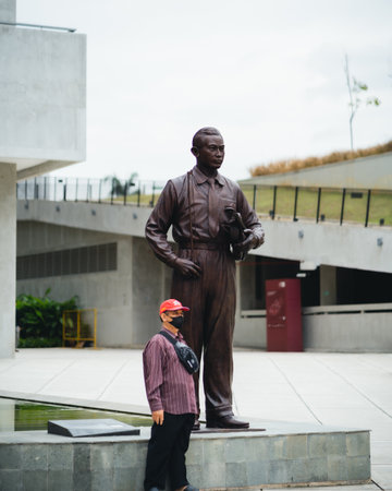 "Jakarta, Indonesia - October 2022: a man in a red hat and a striped shirt is taking a photo near the statue of the hero ismail marzuki."のeditorial素材