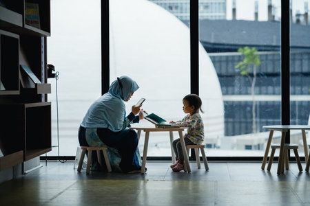 Jakarta, Indonesia - October 2022: a mother is reading a book to her child at the Jakarta library,...