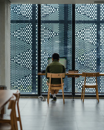 "Jakarta, Indonesia - October 2022: a man is enjoying the facilities of the Jakarta library, he is sitting in the corner and is opening whatsapp on the computer.のeditorial素材
