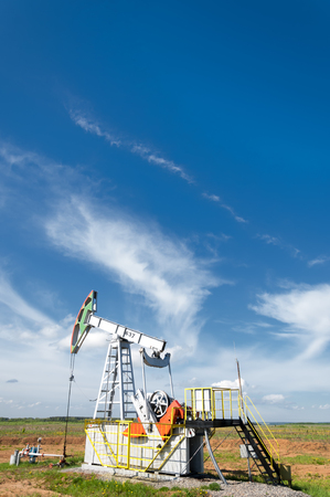 Oil and gas industry. Work of oil pump jack on a oil field. White clouds and blue sky. oil well pump. Oil and gas industry. Work of oil pump jack on a oil field.のeditorial素材