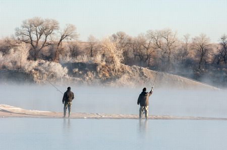 fishermen. A fisherman fight against a bass at sunset. Fisherman silhouette on the beach at colorful sunset. Fly fisherman walking beautiful landscapeの写真素材